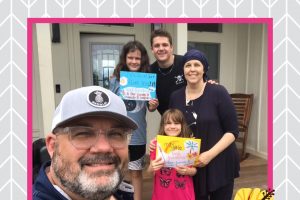 family holding signs in hawaii, man, woman, won, two daughters