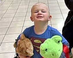 Young boy holding a stuffed bear and a frog