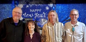 Three men and one woman by a New Year's sign