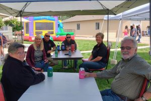 People sitting at tables with a bounce house in the background