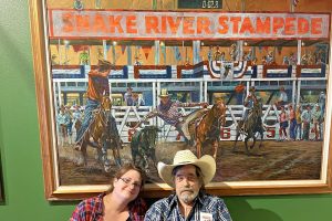 Woman and a man in wheelchair in front of a Snake River Stampede sign