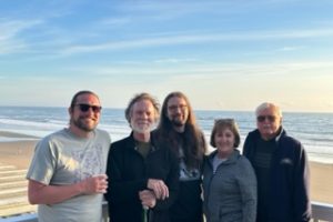 Five people standing on a balcony by the beach