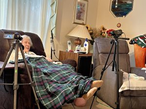 Elderly woman sitting in a recliner with audio equipment surrounding her