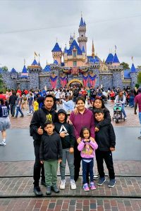 A family of 7 standing in front of Cinderella's castle at Disneyland