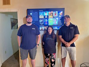 A woman and two men standing in front of a TV