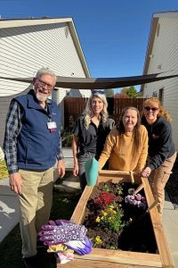 Four people (one man, three women) gathered around a planter box