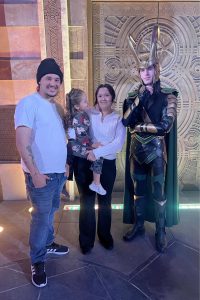 A man, woman, and child next to a Disney character
