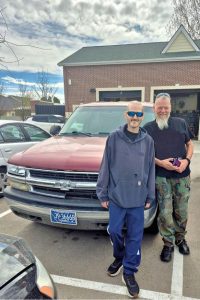 Two men standing in front of a car