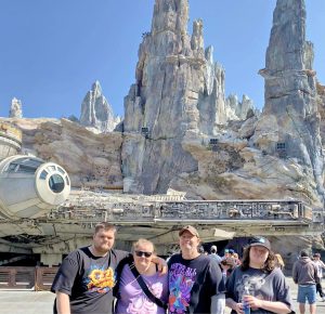 Four people standing in front of a Star Wars ride in Disneyland