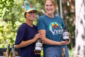Two women showing off bottles of wine