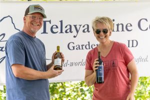 Two people holding up wine bottles