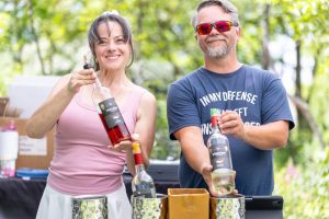 Two people holding up wine bottles