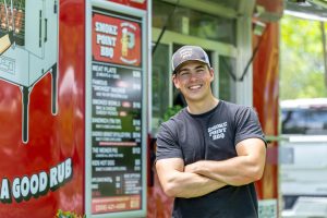 A man standing in front of a BBQ food truck