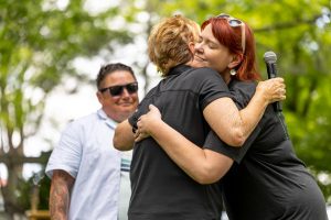 Two women hugging while another looks on