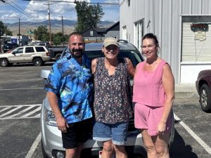 Three people standing in front of a car